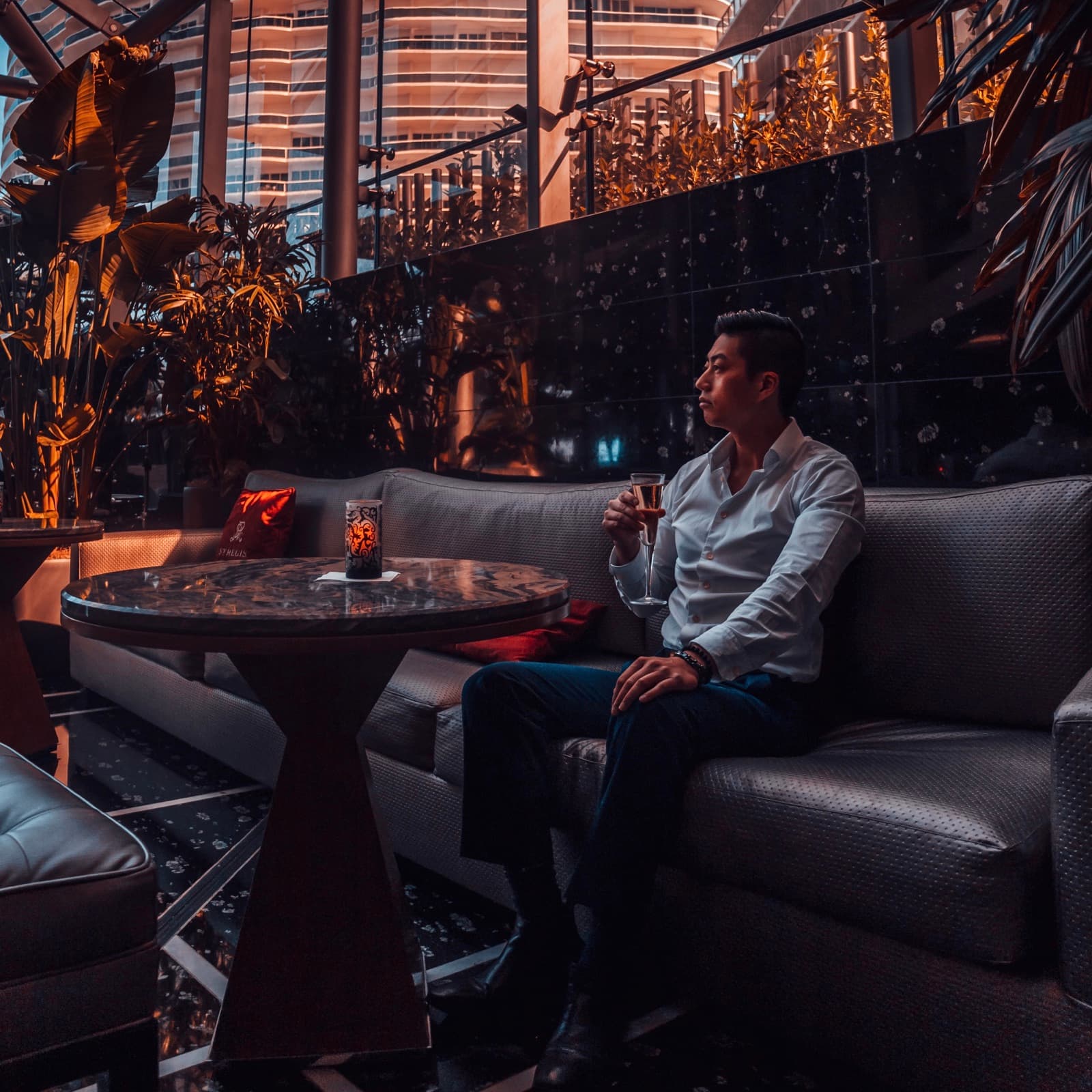 Larry Nguyen in a lounge at dusk, city lights behind glass